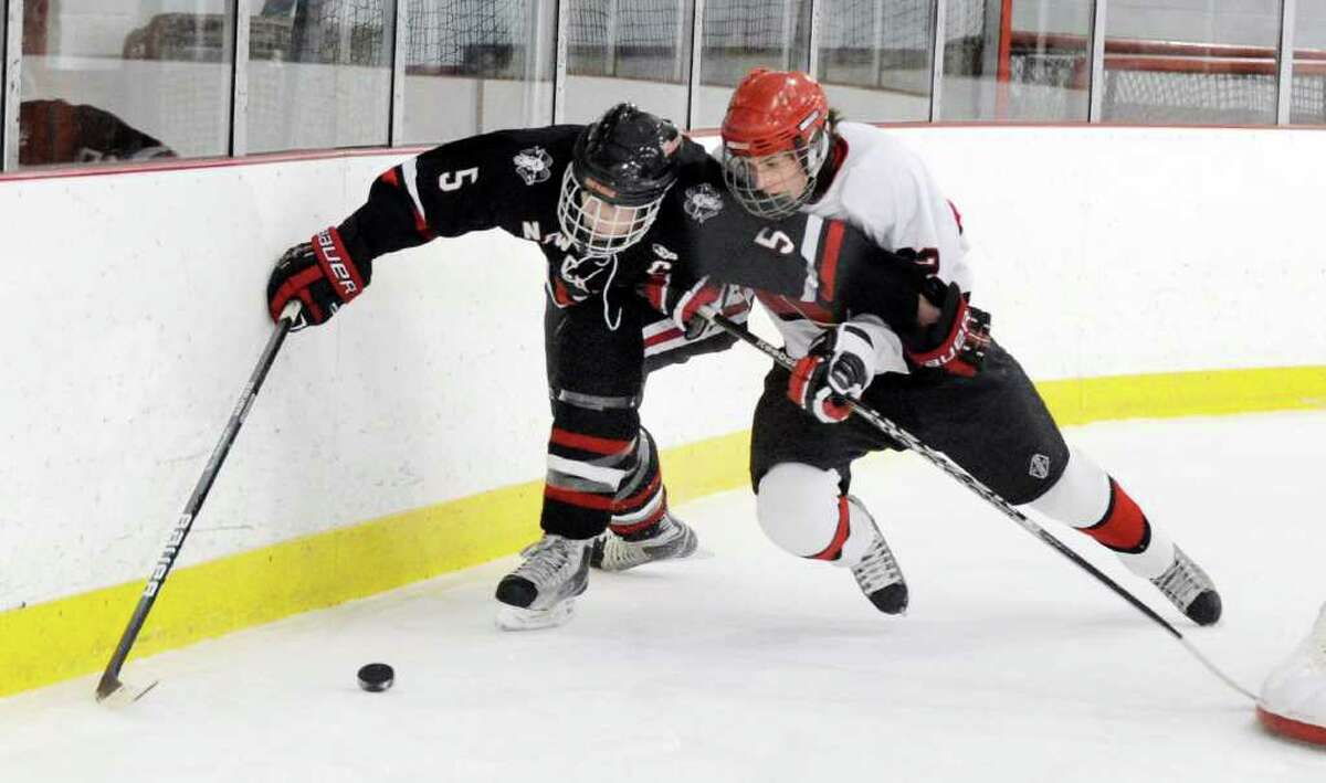 Thomas Krieger, # 5 of New Canaan High School, left, fights Ryan Corrigan, # 22 of Greenwich High Shool, right for the puck during hockey game between Greenwich High School vs. New Canaan High School at Hamill Rink, Byram, Thursday night, Dec. 23, 2010.