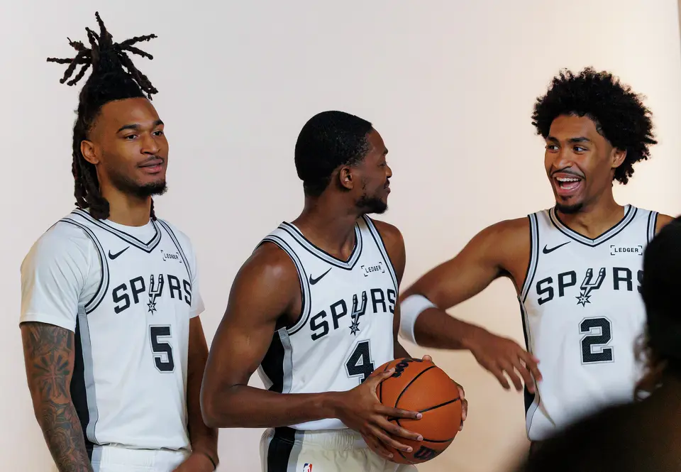 San Antonio Spurs guards Stephon Castle (5), De’Aaron Fox (4) and Dylan Harper (2) joke around after taking portraits together during the NBA basketball team’s media day at the Victory Capital Performance Center in San Antonio, Monday, Sept. 28, 2026.