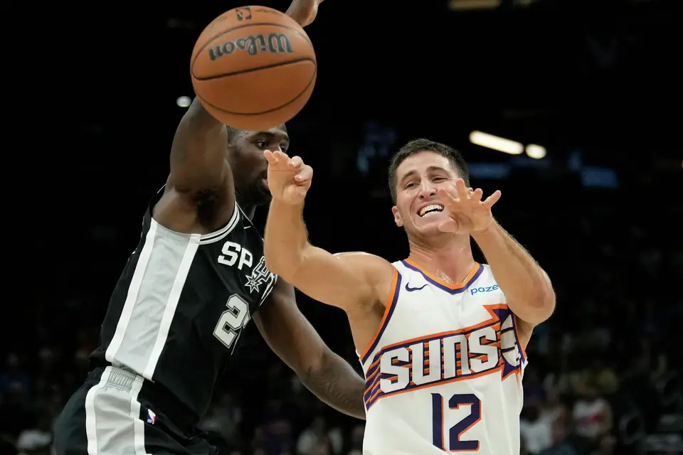 Phoenix Suns guard Collin Gillespie (12) passes the ball against San Antonio Spurs forward David Jones Garcia during a preseason NBA basketball game, Saturday, Oct. 10, 2026, in Phoenix. (AP Photo/Ross D. Franklin)