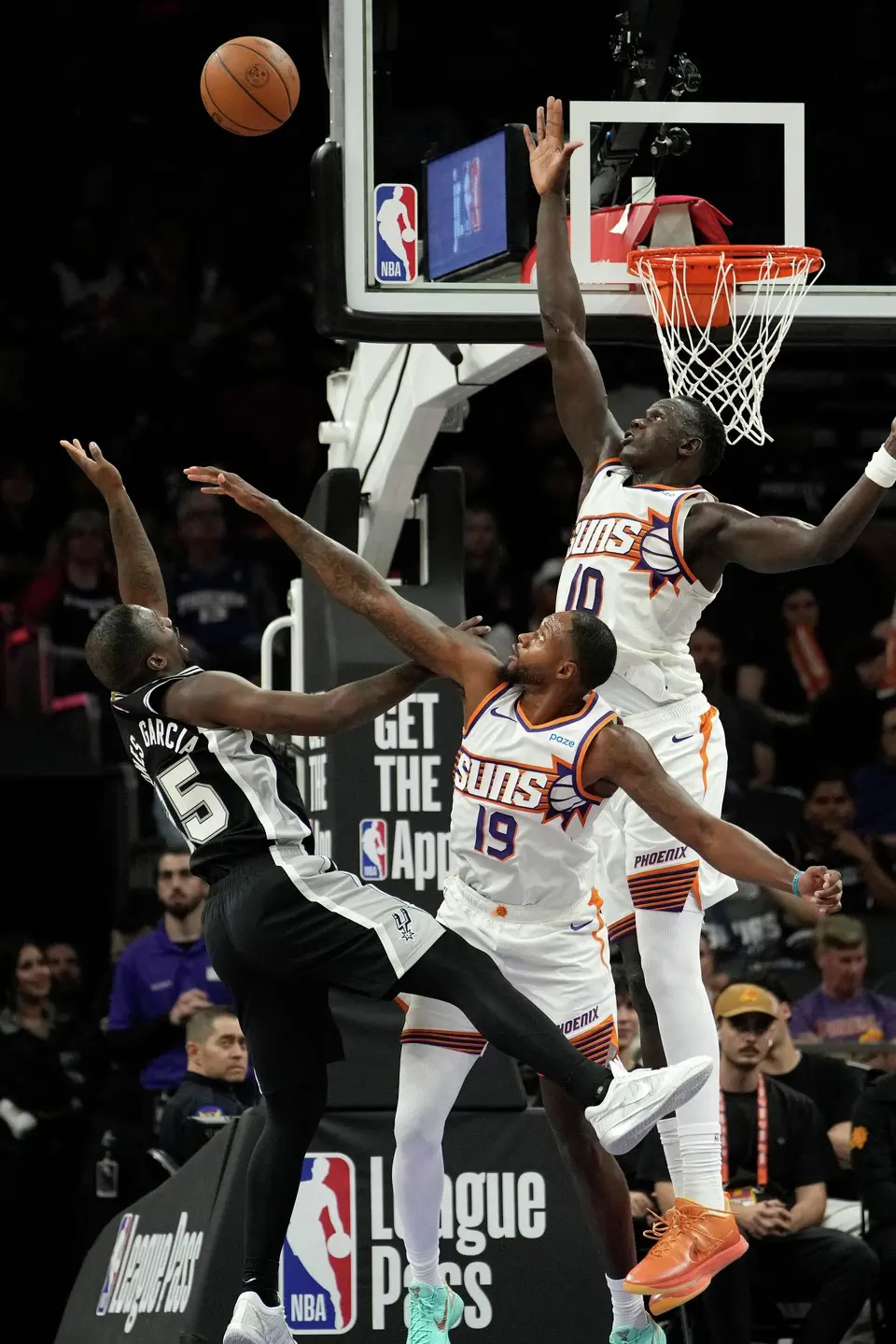 Phoenix Suns forward Haywood Highsmith (19) and Suns center Khaman Maluach (10) defend on a shot by San Antonio Spurs forward David Jones Garcia, left, during a preseason NBA basketball game, Saturday, Oct. 10, 2026, in Phoenix. (AP Photo/Ross D. Franklin)