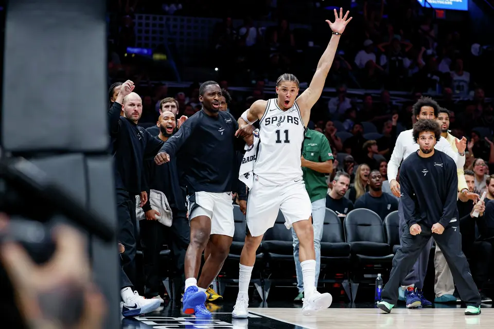 San Antonio Spurs guard David Jones Garcia, from left, forward Carter Bryant (11) and other Spurs players react to a dunk made by guard De'aaron Fox (4) during the second quarter of a preseason NBA game against the Phoenix Suns at Frost Bank Center in San Antonio, Wednesday, Oct. 14, 2026.