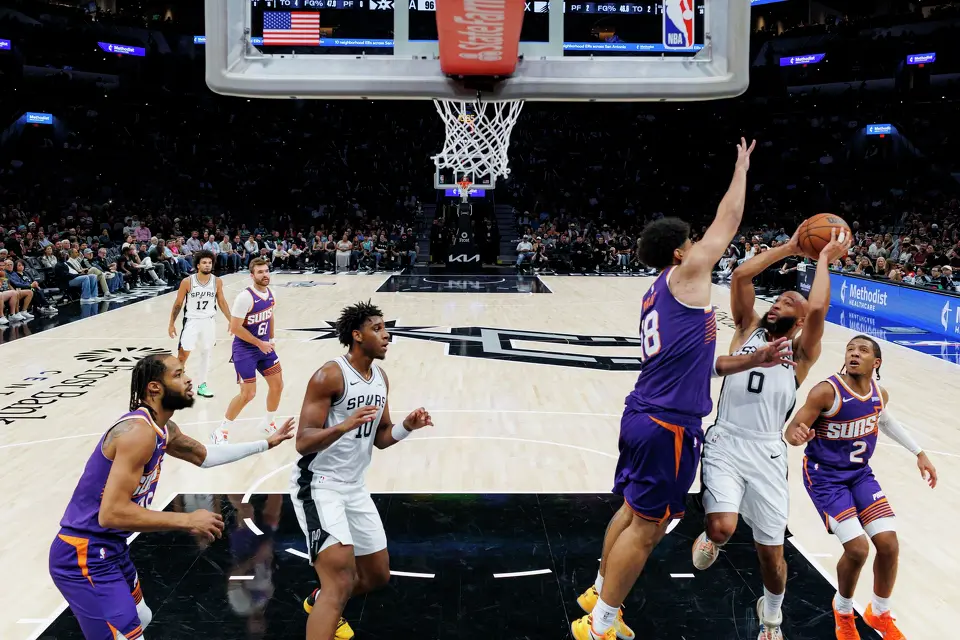 San Antonio Spurs guard Jordan McLaughlin (0) goes up for a shot around Phoenix Suns forward Koa Peat (18) during the second half of a preseason NBA game at Frost Bank Center in San Antonio, Wednesday, Oct. 14, 2026. The Spurs defeated the Suns 123-103.