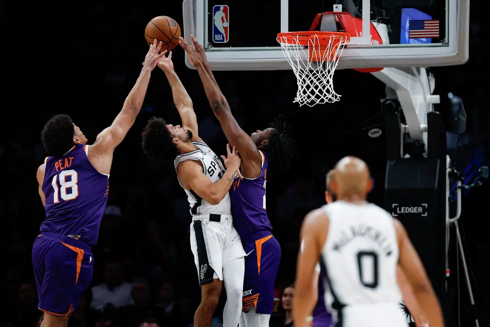 San Antonio Spurs guard Ja'kobi Gillespie (17) goes up for a shot in-between Phoenix Suns forward Koa Peat (18) and forward CJ Huntley (21) during the second half of a preseason NBA game at Frost Bank Center in San Antonio, Wednesday, Oct. 14, 2026. The Spurs defeated the Suns 123-103.