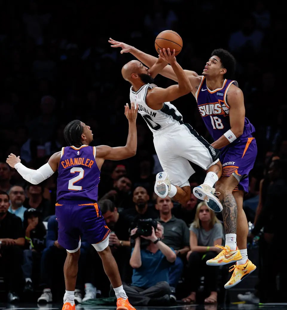 San Antonio Spurs guard Jordan McLaughlin (0) goes up for a shot around Phoenix Suns forward Koa Peat (18) during the second half of a preseason NBA game at Frost Bank Center in San Antonio, Wednesday, Oct. 14, 2026. The Spurs defeated the Suns 123-103.