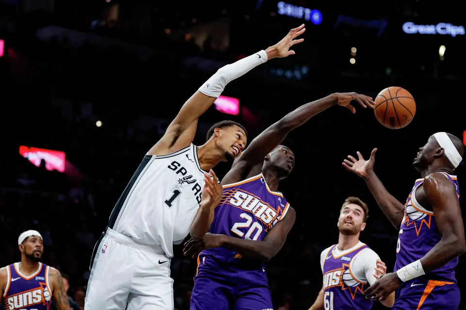 The ball flies over San Antonio Spurs center Victor Wembanyama (1) and Phoenix Suns forward Rasheer Fleming (20) as they fight for the rebound during the first half of a preseason NBA game at Frost Bank Center in San Antonio, Wednesday, Oct. 14, 2026.