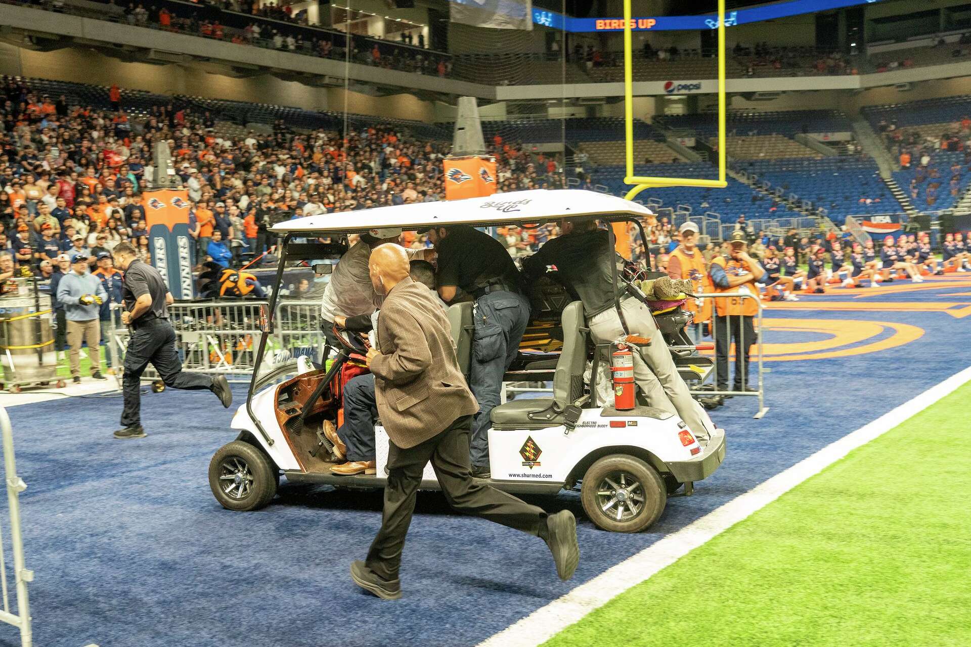 Emergency personnel tend to a military service member who fell from the rafters of the Alamodome while participating in a rappelling demonstration before the UT