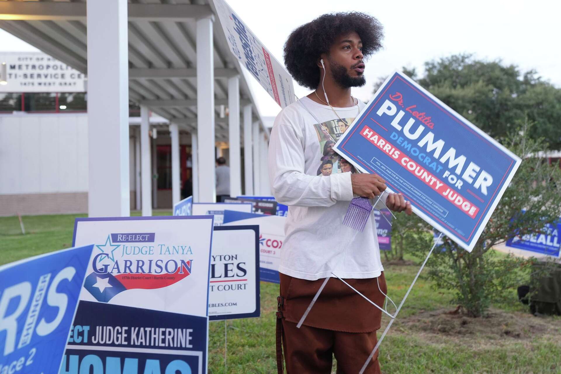 Lawrence Bell II holds signs for candidates at Metropolitan Multi-Service Center in Houston on Monday, Oct. 19, 2026.