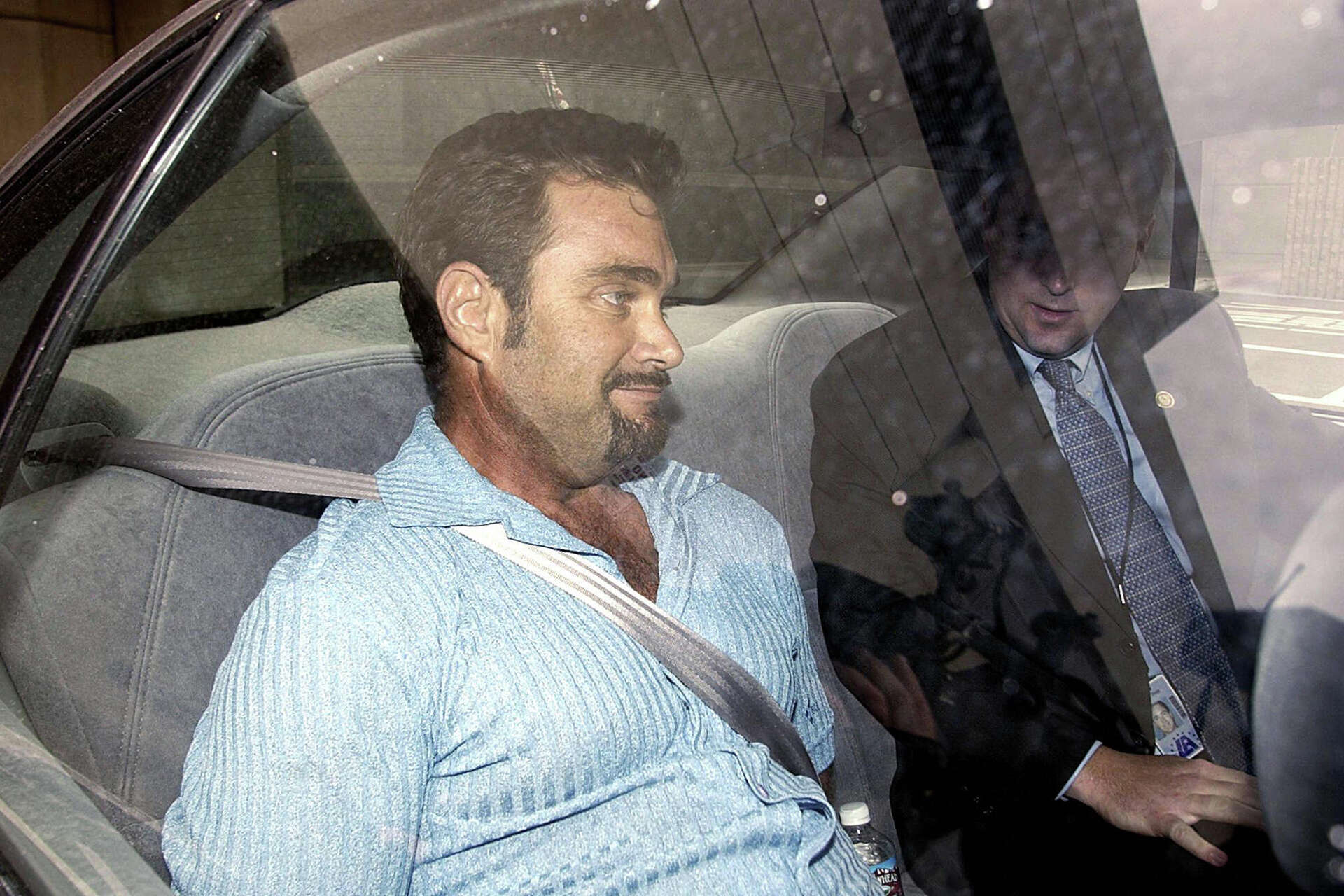 Max Factor fortune heir Andrew Luster rides in a car under FBI escort after arriving June 19, 2003, at Los Angeles International Airport.