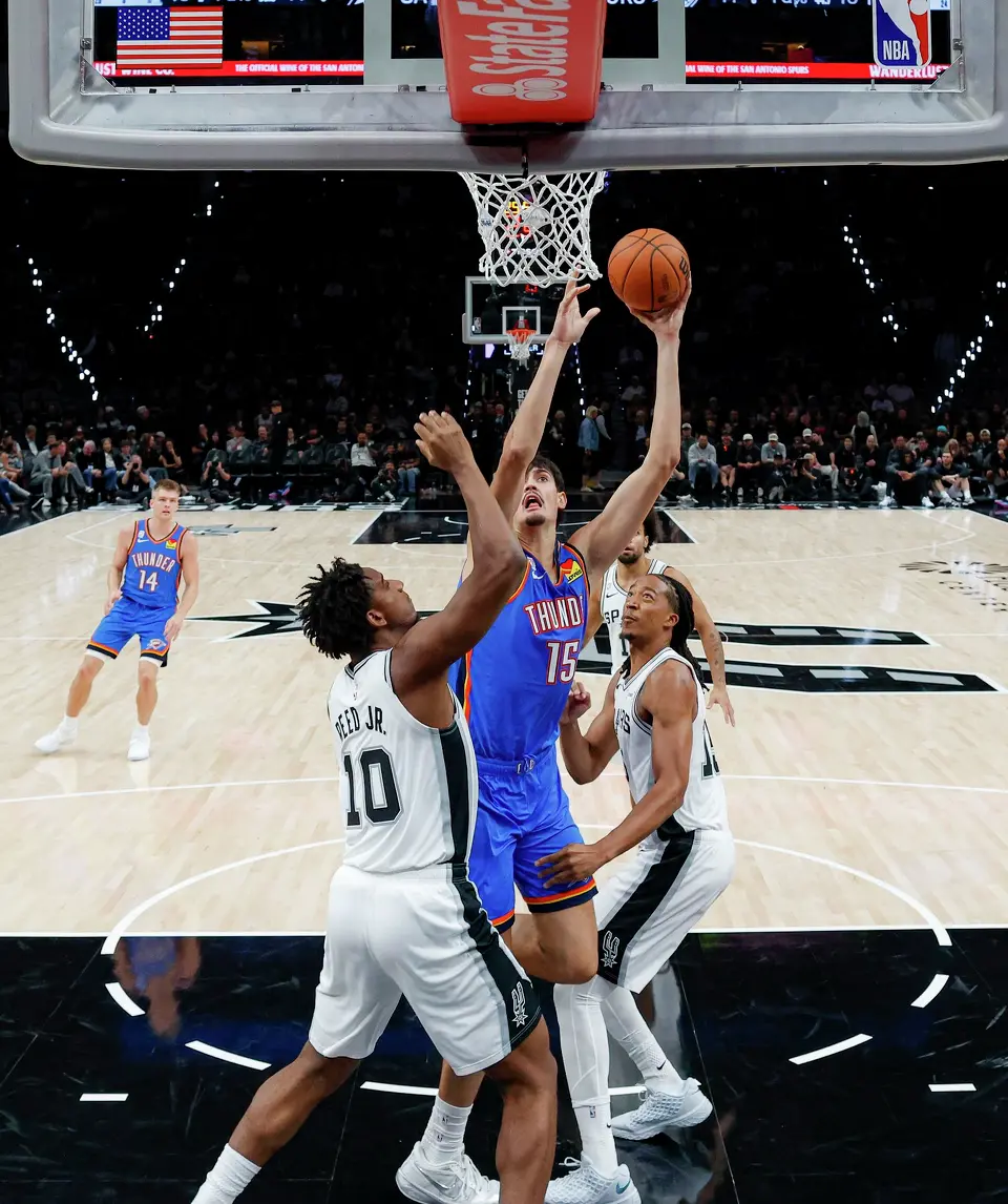 Oklahoma City Thunder center Aday Mara (15) goes up for a shot over San Antonio Spurs center Tarris Reed Jr. (10) and San Antonio Spurs forward Maliq Brown (15) during the second half of the NBA season opener at Frost Bank Center in San Antonio, Tuesday, Oct. 20, 2026. The Spurs fell to the Thunder 116-104.
