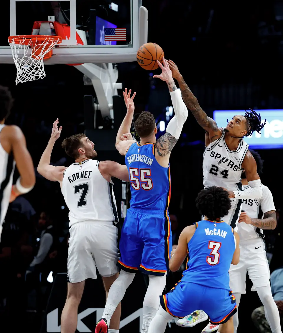 San Antonio Spurs center Luke Kornet (7) and guard Devin Vassell (24) battle Oklahoma City Thunder center Isaiah Hartenstein (55) for a rebound during the second half of an NBA basketball game Tuesday, Oct. 20, 2026, in San Antonio. The Thunder won 116-104.