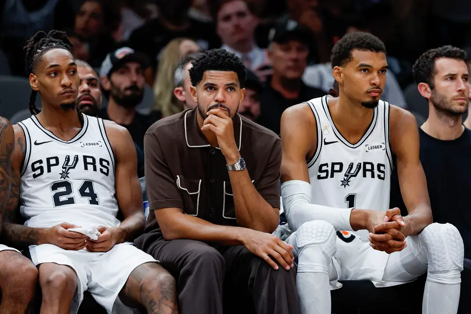 San Antonio Spurs guard Devin Vassell (24), from left, forwards Tobias Harris and Victor Wembanyama (1) watch their teammates play against the Oklahoma City Thunder during the second half of the NBA season opener at Frost Bank Center in San Antonio, Tuesday, Oct. 20, 2026. The Spurs fell to the Thunder 116-104.