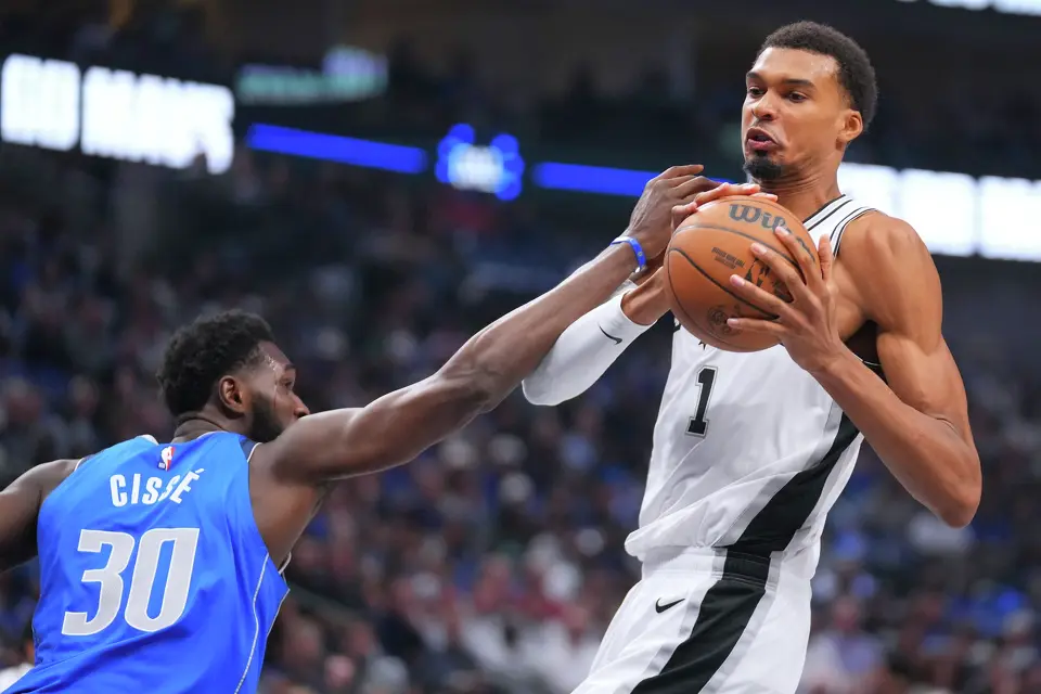 San Antonio Spurs forward Victor Wembanyama, right, tries to control the ball after a rebound as Dallas Mavericks center Moussa Cisse tries to disrupt him during the first half of an NBA basketball game Saturday, Oct. 24, 2026, in Dallas. (AP Photo/Julio Cortez)