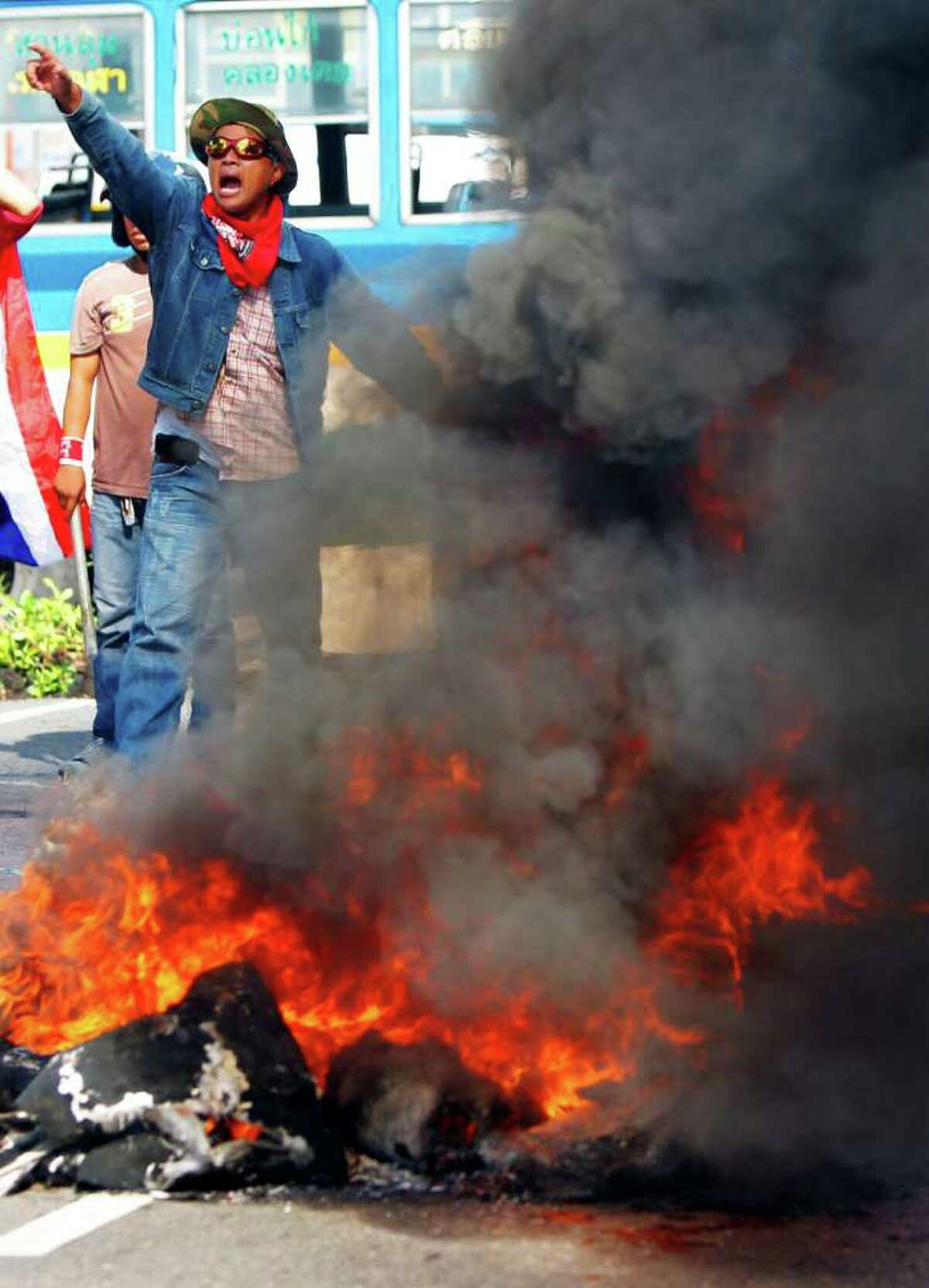BANGKOK, THAILAND - APRIL 13: Red shirt protesters burn tyres as members of theThai military take over the streets during violent protests on April 13, 2009 in Bangkok, Thailand. Anti-government protesters clashed with the military on the streets of Thailand's capital after the government declared a state of emergency. The pro-Shinawatra demonstrators are calling for the resignation of Prime Minister Abhisit Vejjajiva and for fresh elections to be held. (Photo Paula Bronstein/Getty Images)