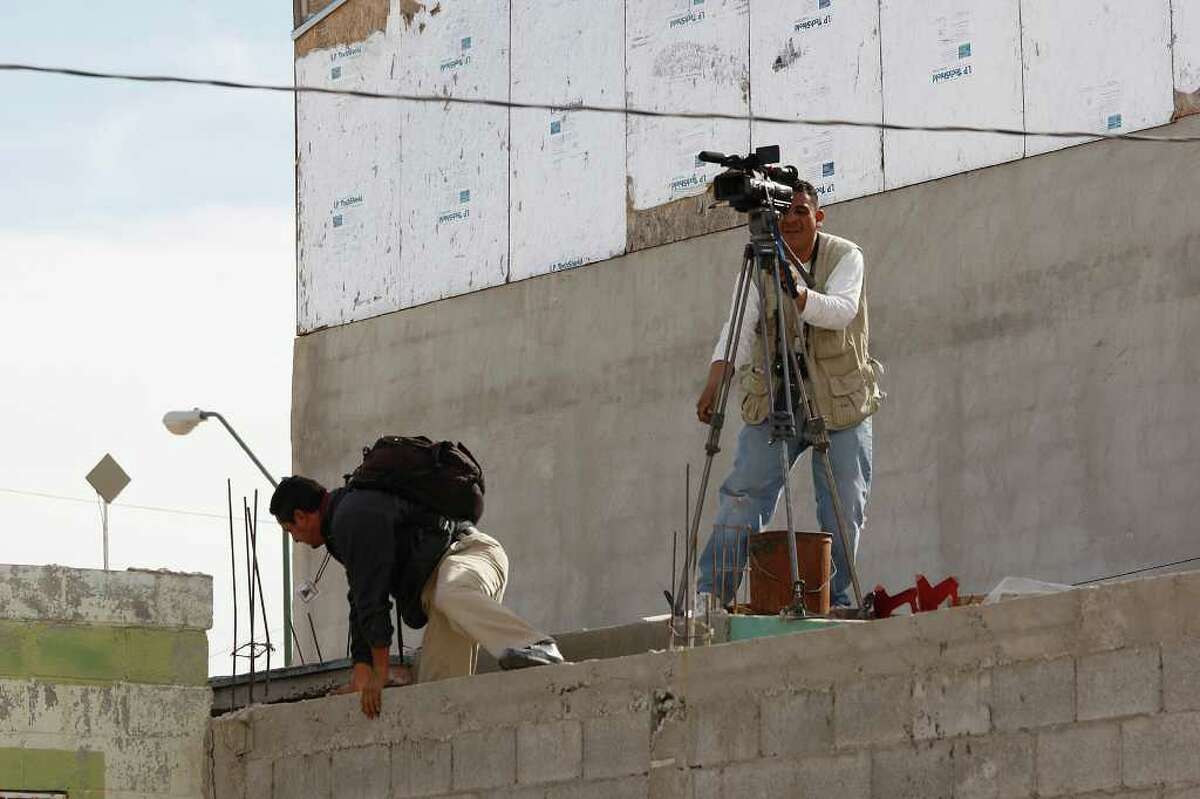 Media members find a vantage point after being driven from a scene where four police died in Ciudad Juárez, Mexico.