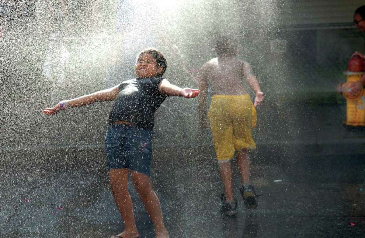 Nine-year-old Taina Melecio cools off in the spray from an open fire hydrant in front of her home on Noble Avenue in Bridgeport Friday June 25, 2010.