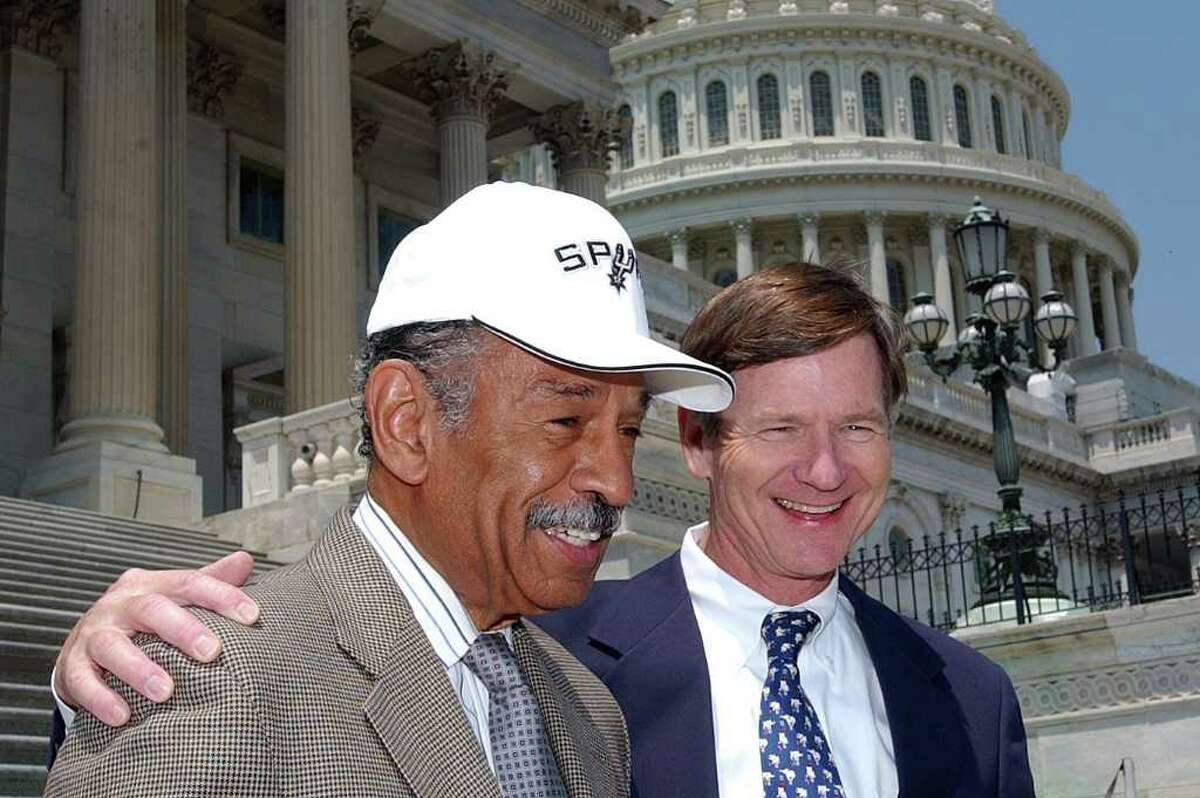 Rep. John Conyers, D-Mich., left, sports a San Antonio Spurs cap on Capitol Hill Friday, June 24, 2005, after losing a NBA Finals bet to Rep. Lamar Smith, R-Tex. The Spurs defeated the Detroit Pistons in game seven of Thursday night's NBA Finals.