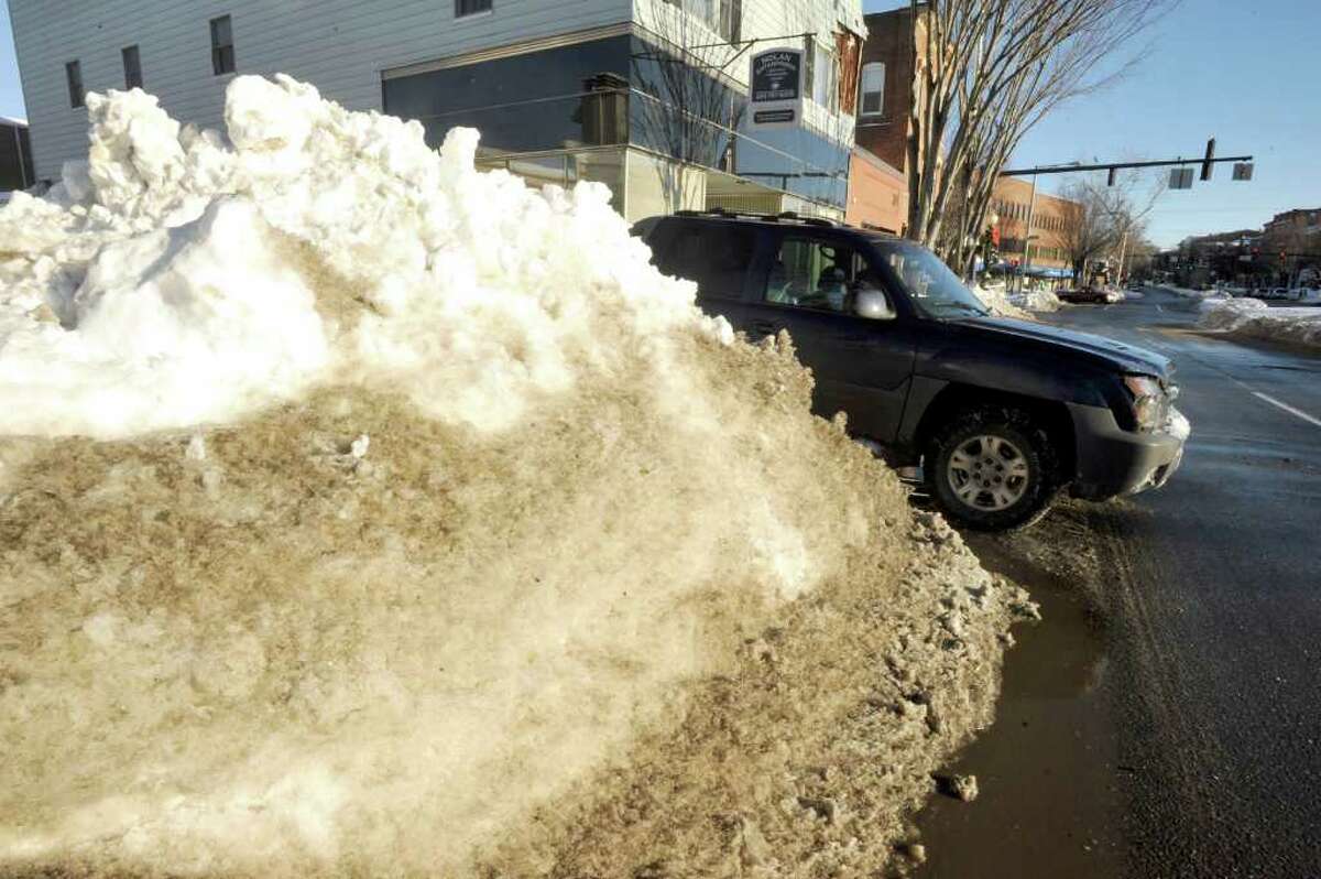 A driver pulls onto Main Street, Danbury, past piles of snow, Thursday, Jan. 13, 2011.