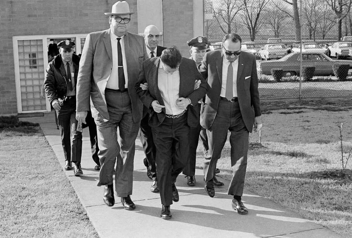 James Earl Ray lowers his head as State Safety Commissioner Greg O'Rear, white hat, and Highway Patrol Maj. Mickey McGuire, dark glasses, lead him to prison in Nashville, Tenn., March 11, 1969. Ray is serving a 99-year sentence in the death of Dr. Martin Luther King, Jr. in Memphis. (AP Photo)