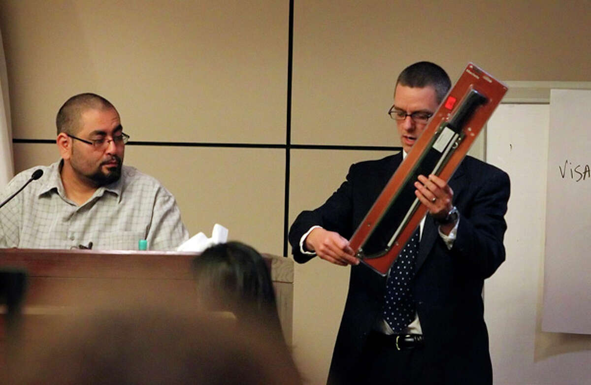 Bexar country prosecutor Christian Henricksen (right) holds an example of a machete that was purchased from a Southside Wal-Mart during the questioning of Wal-Mart employee Ruben Naranjo in the murder trial of Thomas Ahrens on Jan. 13.