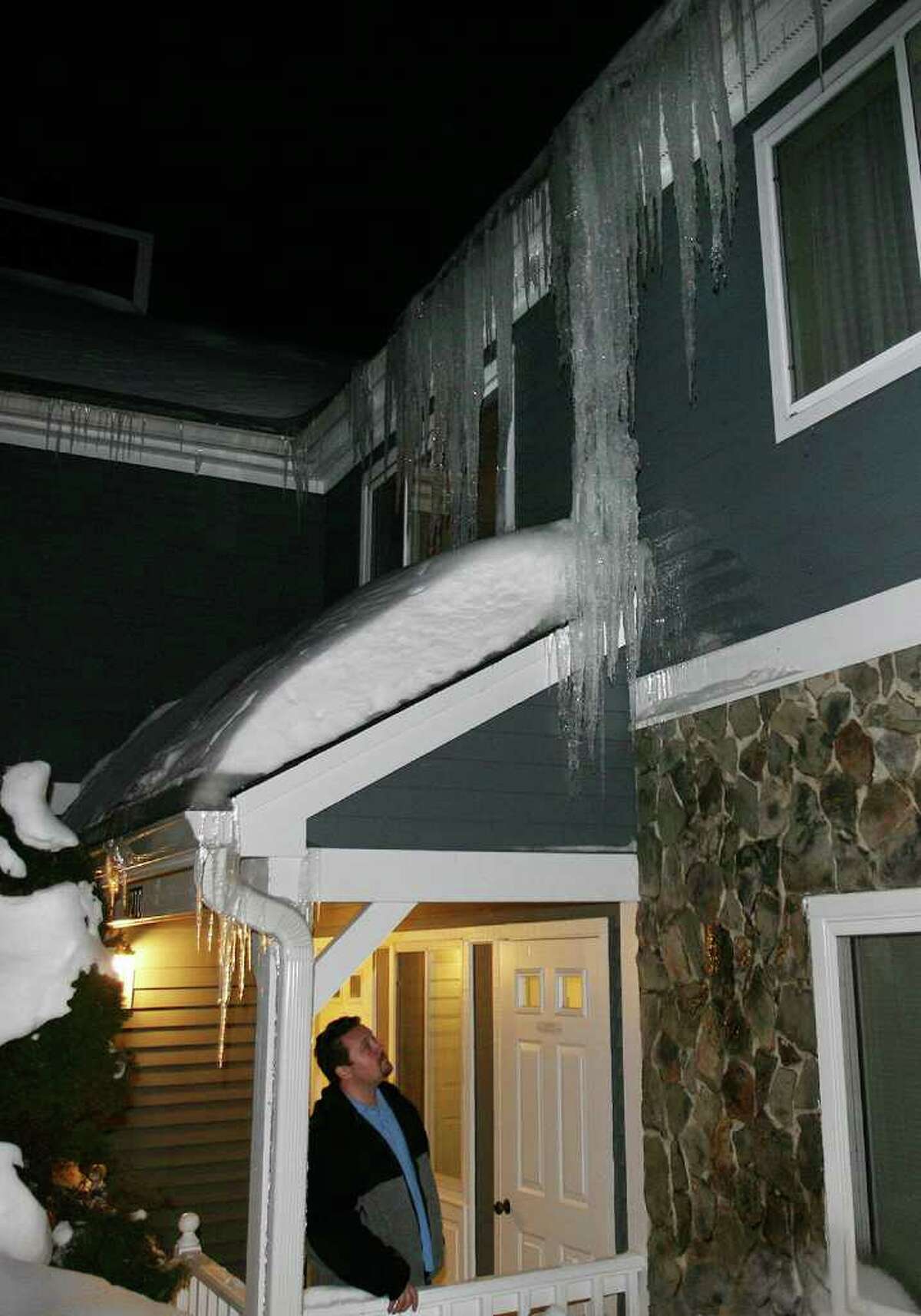 J.P. Sredzinski of Monroe looks at giant icicles hanging from gutters blocked with ice outside his condo in the Hills of Monroe complex on Monday, January 17, 2011.