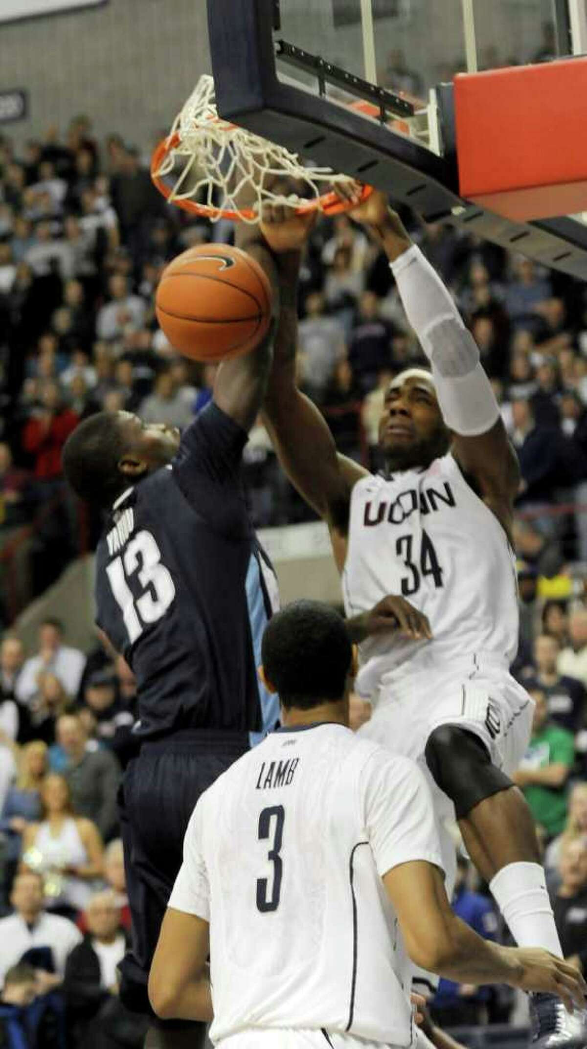 Connecticut's Alex Oriakhi dunks the ball as Villanova's Mouphtaou Yarou of Benin tries to stop him in the first half of an NCAA men's college basketball game at Storrs, Conn., Monday, Jan. 17, 2011. Watching is Connecticut's Jeremy Lamb. (AP Photo/Bob Child)