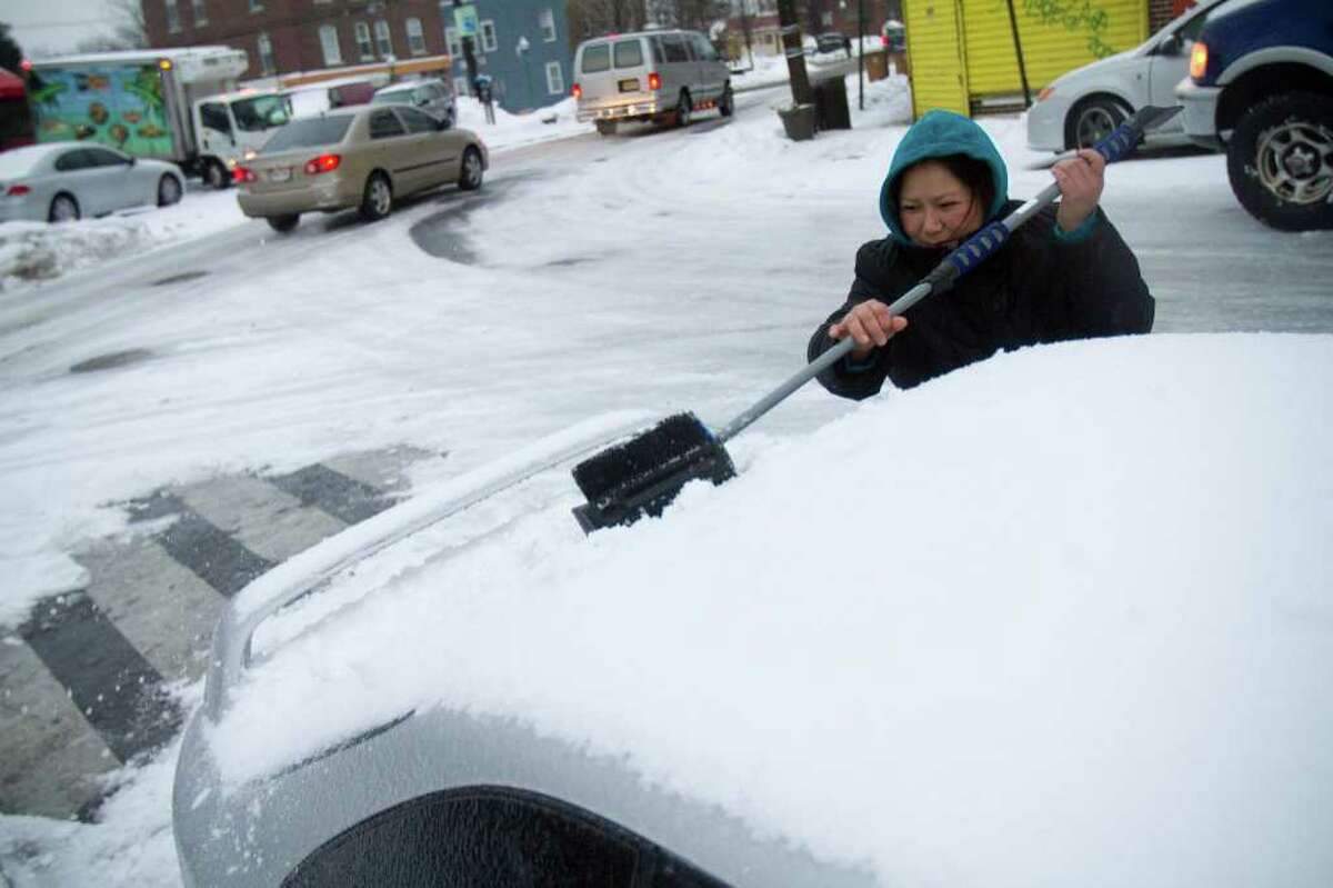 Maura Castro sweeps snow off of her car during a snow and ice storm in Stamford, Conn. on Tuesday, Jan. 18, 2011.