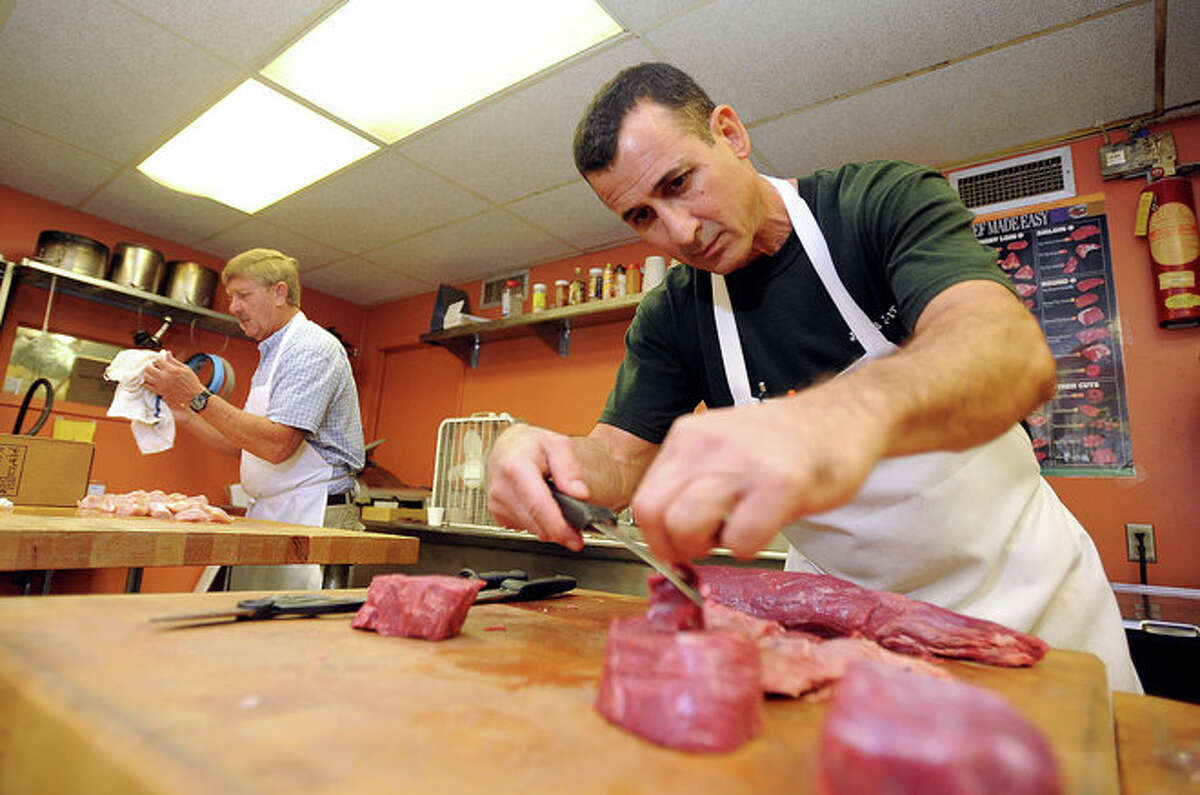 From left, Robert Boehme and Louis Blanda trim meat at Jack-Pack-It on Tuesday. Although suffering home damage, Blanda re-opened the store's doors shortly after Hurricane Ike hit offering food supplies to the public. Guiseppe Barranco/The Enterprise