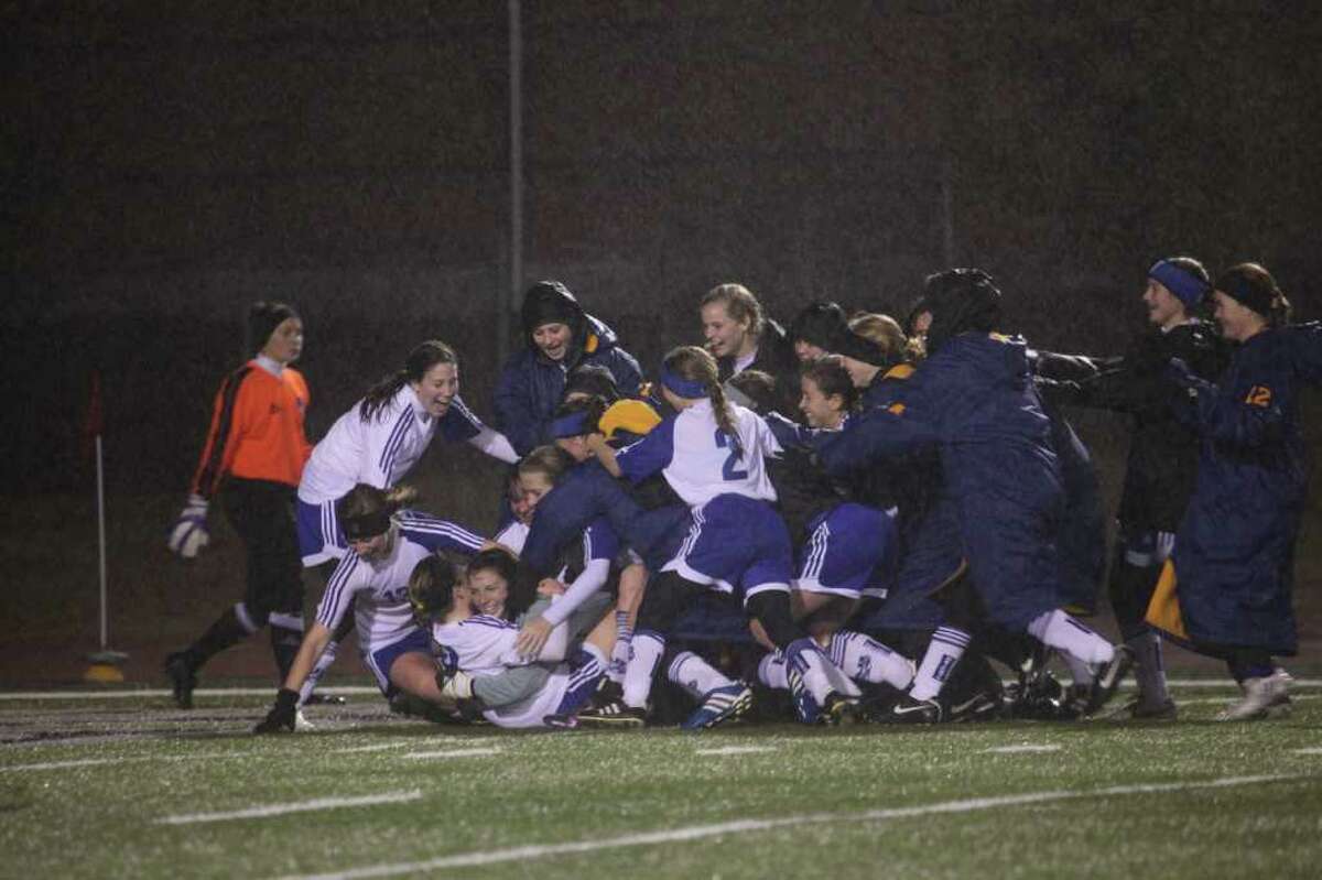 Alamo Heights soccer goalkeeper Chloe Crumley (gray shirt, on ground) is embraced by her teammates in celebrating their Comal Cup championship win last weekend. The Mules won a sudden death shootout after going scoreless with Waco Midway through regulation play.Photo by Mary Candee