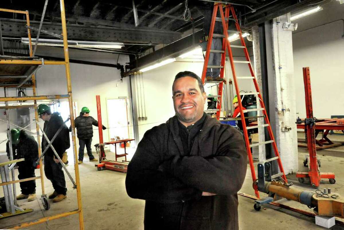 Carlos Espinal stands in his new business, Extreme Auto Body and Collision, in Danbury, Monday, Jan. 24, 2011. Henry Abbott Technical School electrical students work in the background.