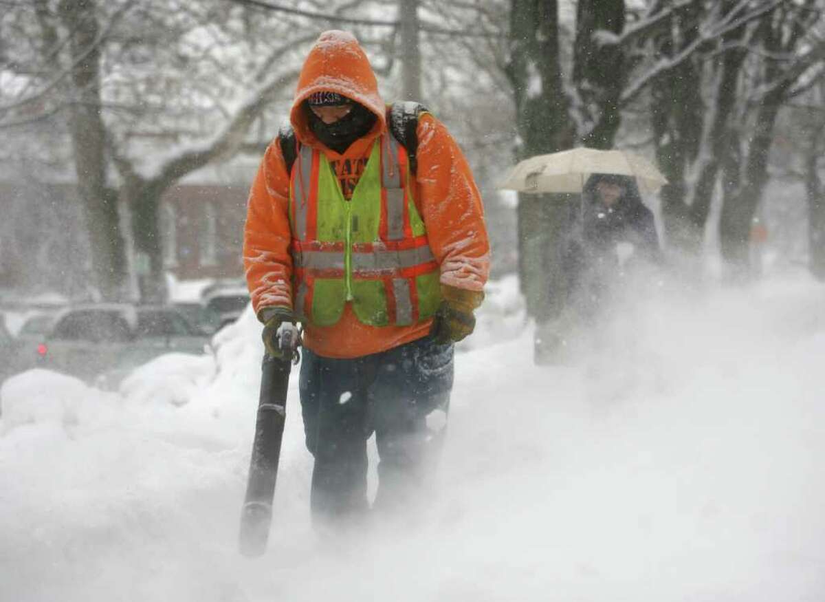 Milford public works employee J.R. Flores uses a handheld blower to keep the sidewalks clear in front of the Parsons Government Complex in downtown Milford on Tuesday, January 25, 2011.