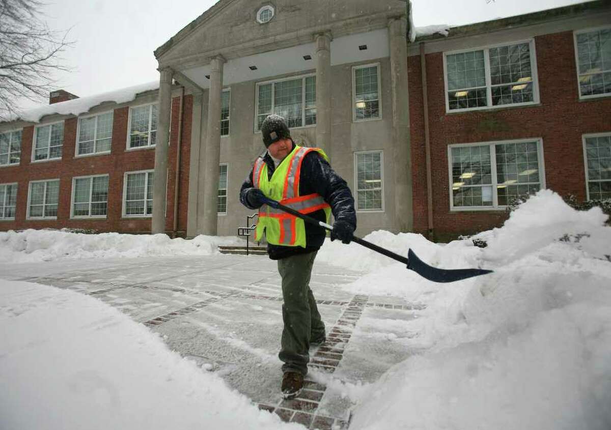 Milford public works employee Brian Wasilnak shovels snow in front of the Parsons Government Complex in downtown Milford on Tuesday, January 25, 2011.