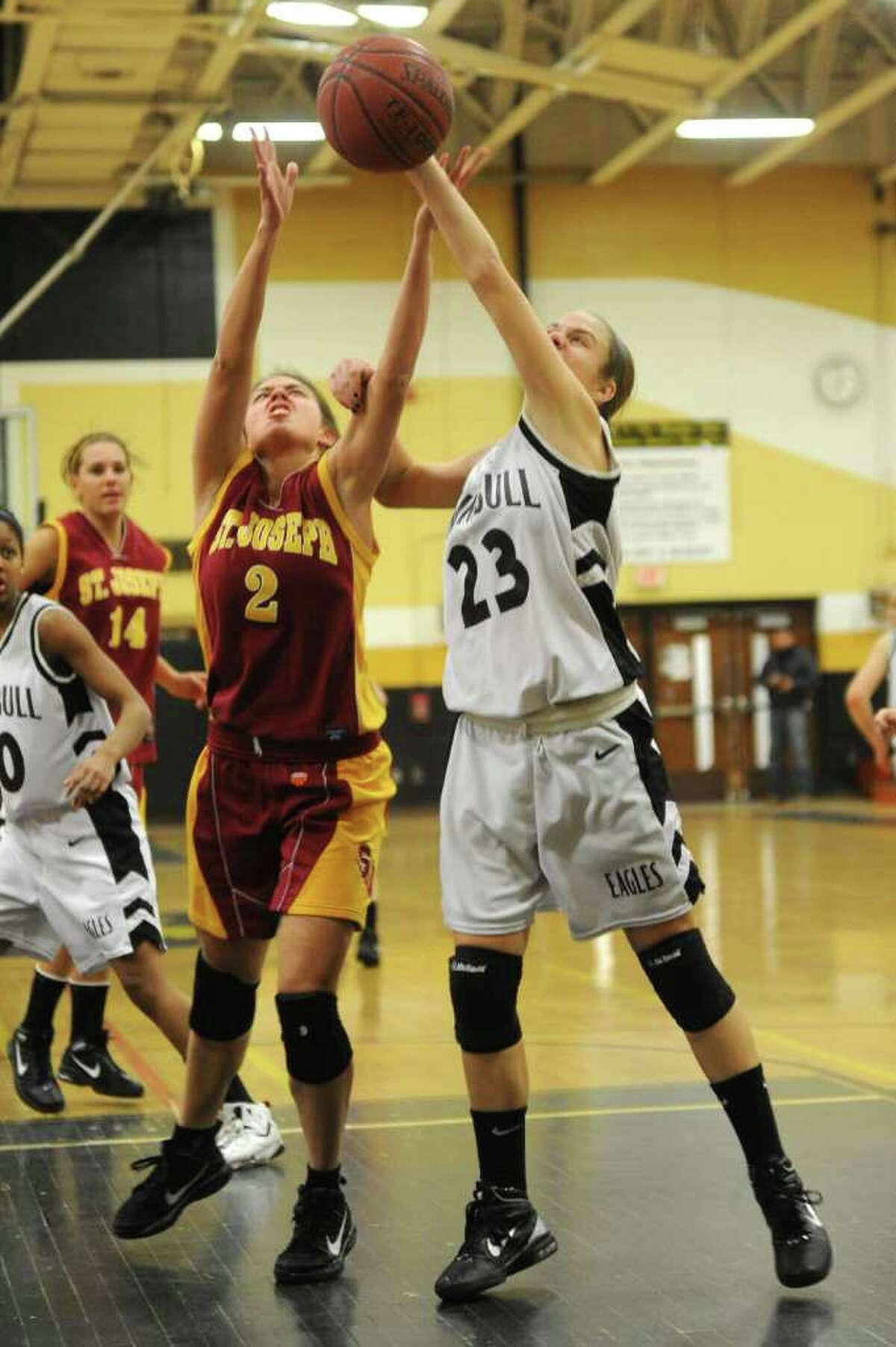 St. Joseph's Jess Jowdy, left, and Trumbull's Victoria Pfohl, right, reach for a rebound during Tuesday's game at Trumbull High School on January 25, 2011.