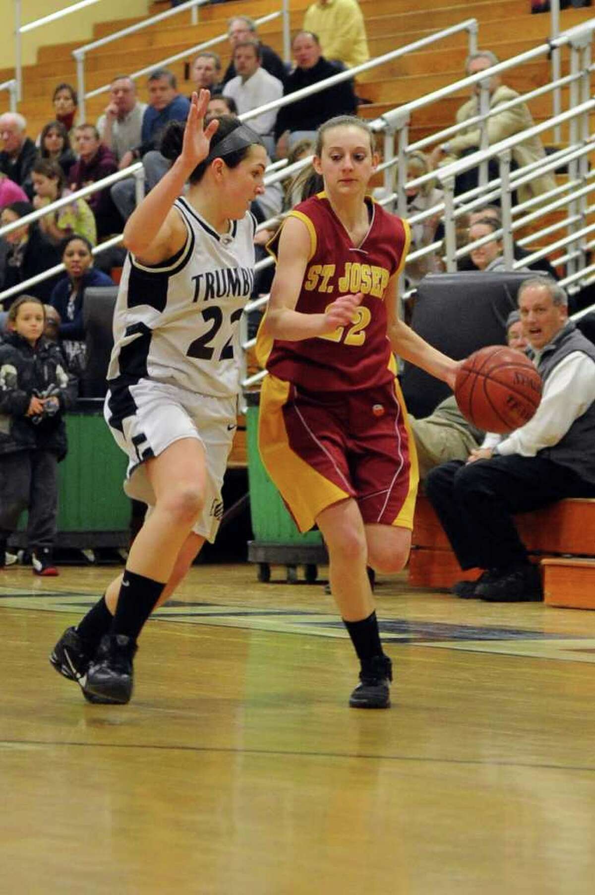 St. Joseph's Nancy Stablein dribbles as she is defended by Trumbull's Kelly Coughlin during Tuesday's game at Trumbull High School on January 25, 2011.