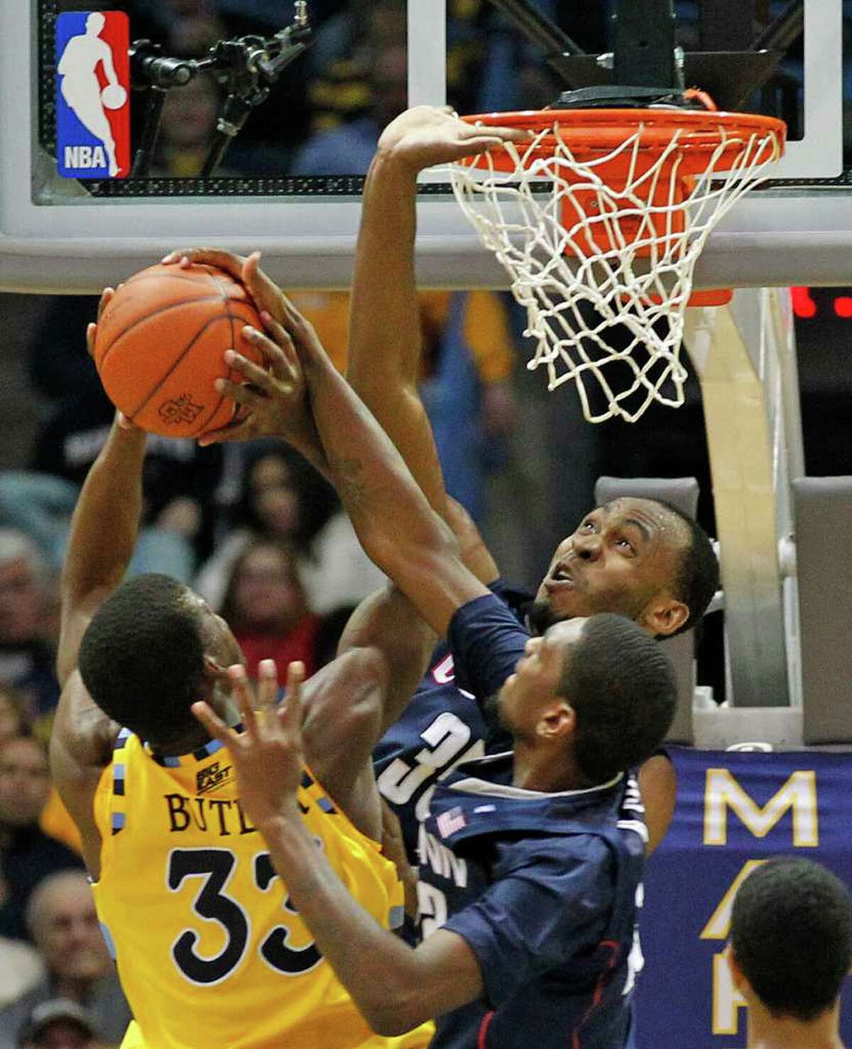 Connecticut's Charles Okwandu (35) and Roscoe Smith (22) defend against Marquette's Jimmy Butler (33) in the second half of an NCAA college basketball game Tuesday, Jan. 25, 2011, in Milwaukee. (AP Photo/Jeffrey Phelps)