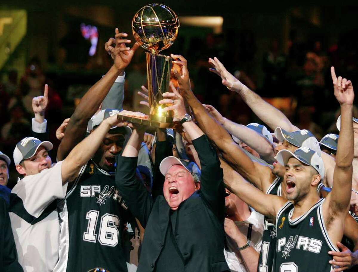 San Antonio Spurs owner Peter Holt (C) holds up the Larry O'Brien Trophy with players Tony Parker (R) and Francisco Elson