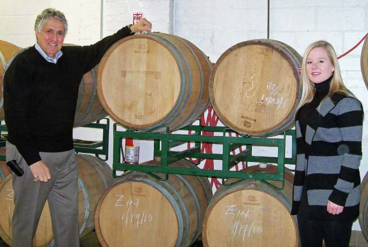 Tony Izzo, left, and one of his employees, Jessica Beale, and the oak barrels at Black Rock Vintners where the winery's award-winning wine is aged.