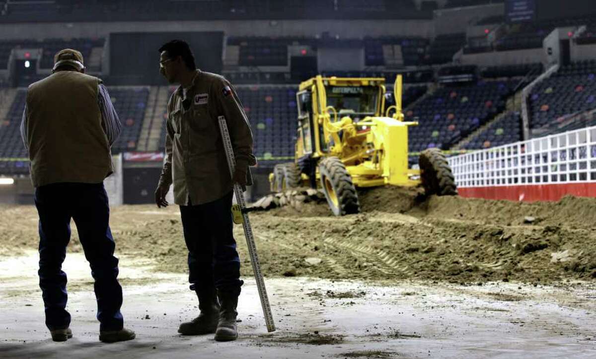 Metro daily - Andy Cordova, right, of Unison Drilling holds a measureing stick as he talks to Bill McDonald, left, of the Operations Committee of the Stock Show and Rodeo. Workers dump and spread 2,160 tons of soil from Charlotte, TX, in the ATT Center in preparation for the San Antonio Stock Show and Rodeo, Monday, Jan. 31, 2011. photo Bob Owen/rowen@express-news.net
