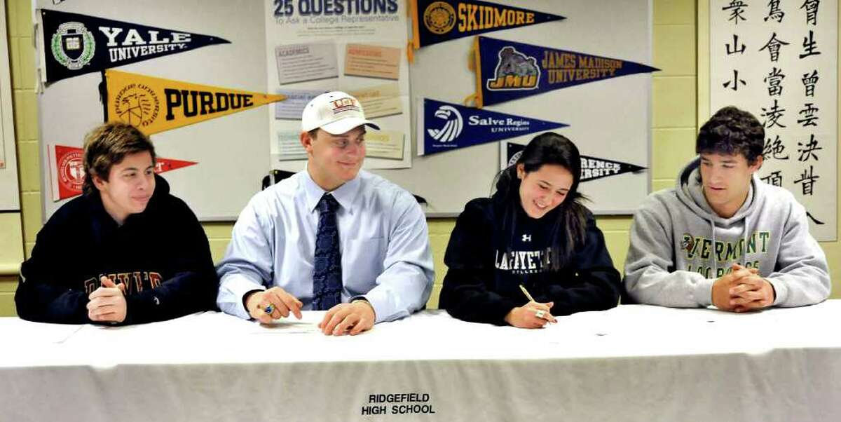 Aidan Scott, left, Tommy Jordan, left center, Jaclyn Giordano, and Andrew Buckanavage, right, sign letters of intent at Ridgefield High School, Friday, Feb. 4, 2011.