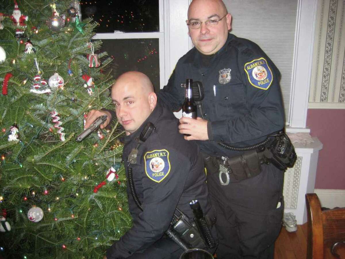 Officer Sean Slingerland, left, who is now a detective, holds a gun while standing with Officer Charles Batchelor at the residence of Robert Schunk. On-duty officers assigned to the city's Strategic Deployment Unit sometimes gathered at Schunk's residence to socialize while on duty.