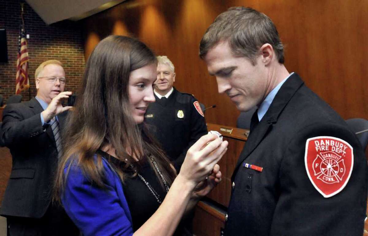 John Halas's girlfriend, Aly Meeker, pins the badge of lieutenant on him during a Danbury Fire Department ceremony in City Hall, Monday, Feb. 7, 2011. Mayor Mark Boughton and Fire Chief Geoff Herald look on.