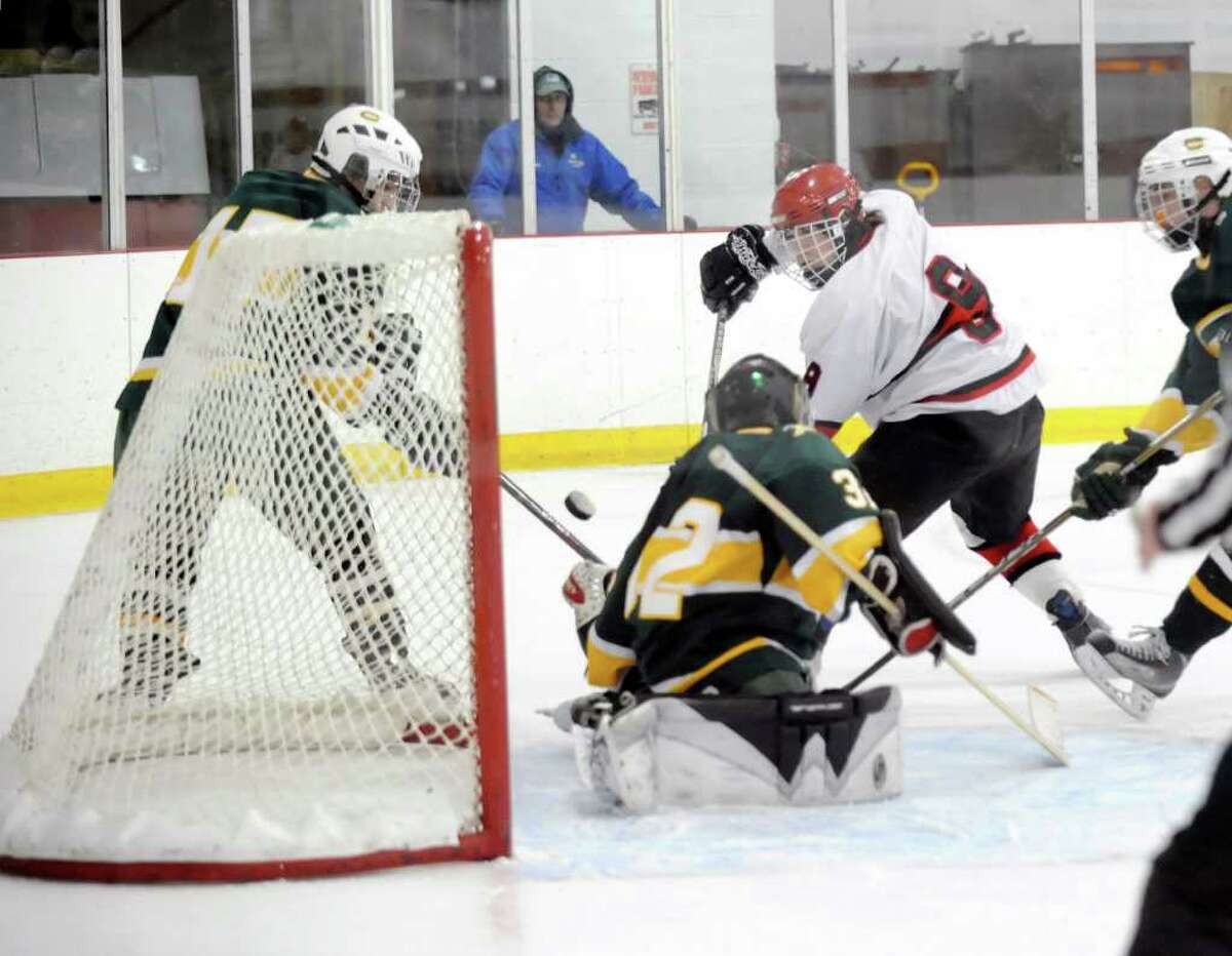 Alex Liebers, # 9, of Greenwich High School, center, attempts a shot that is blocked by Trinity Catholic goalie, Ben Fumega, # 32, during first period action of the Greenwich High School vs. Trinity Catholic High School boys hockey game, at Dorothy Hamill Rink, Byram, Tuesday afternoon, Feb. 8, 2011