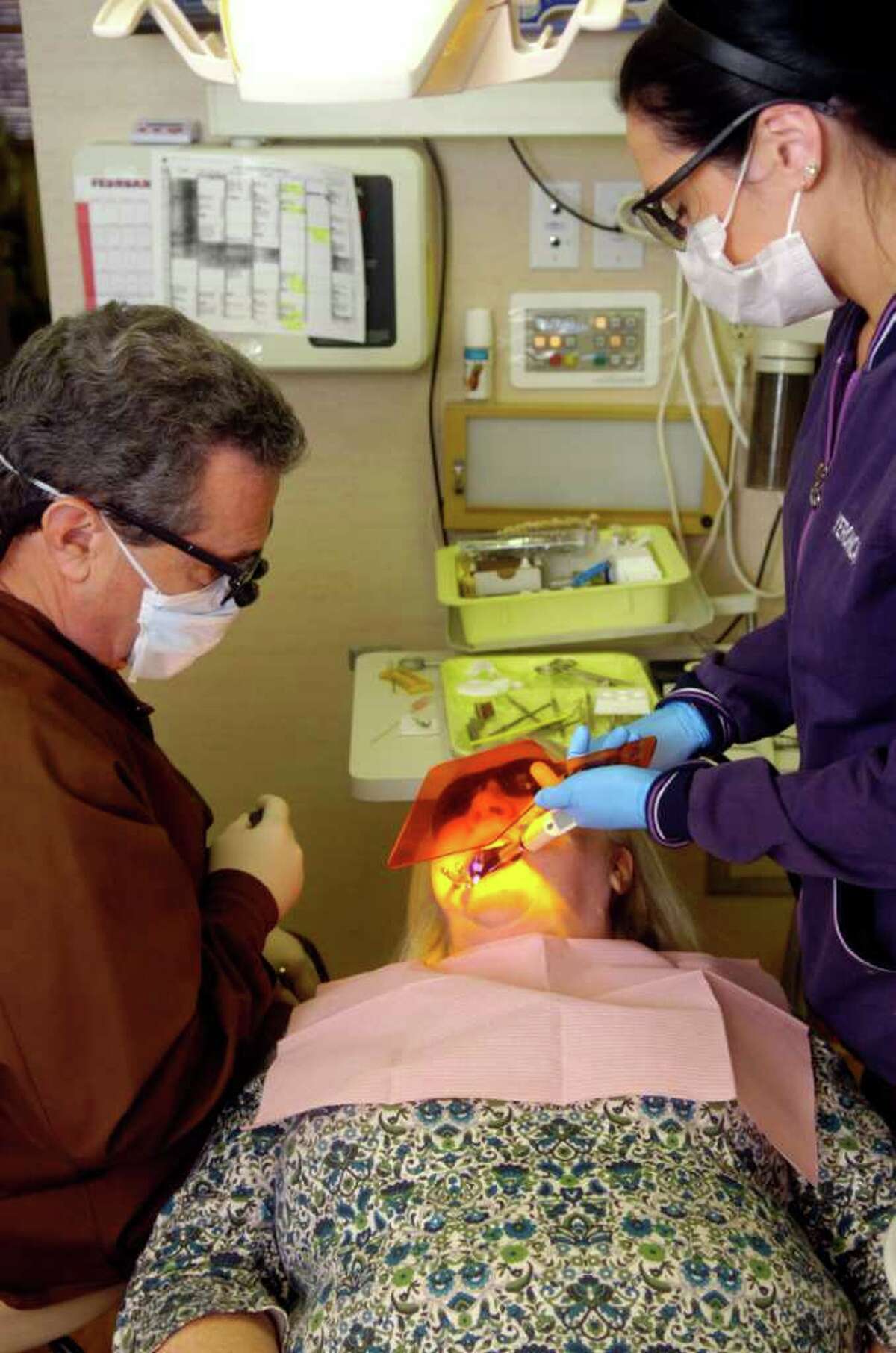 Veronica DeMatties sets a filling in patient Deidre Sullivan as Dr. Joseph Jarmon prepares to customize the filling at Lighthouse Dental Care on Thursday, February 10, 2011.