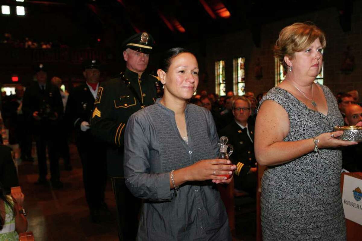 Marianne Velasquez, left, and Laurie Baik, widows of fallen Bridgeport firefighters Lt. Steven Velasquez and Michel Baik, bring communion to the alter during mass at Saint Catherine of Siena in Trumbull. The Diocese of Bridgeport commemorated the ninth anniversary of 9/11 by honoring law enforcement, fire and emergency service personnel in a Blue Mass on Sunday, September, 12, 2010.