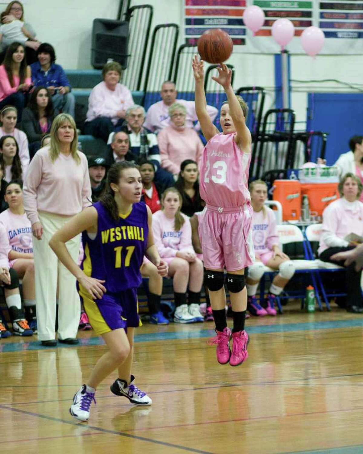 Danbury's Becca Gartner puts up an outside shot during the Cancer Awareness game against Westhill Friday night at Danbury High School. The Westhill defender is Megan D'Alessandro.