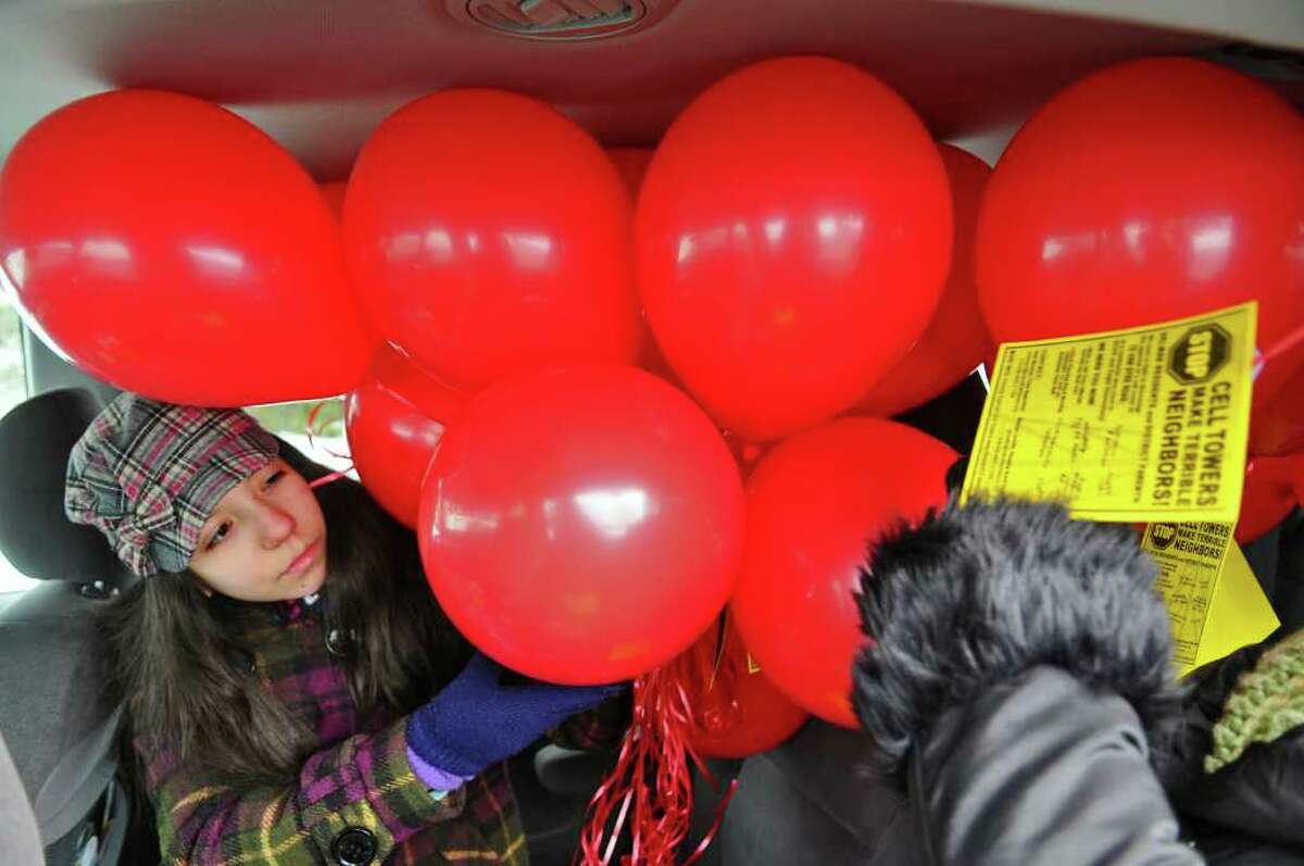 Bethlehem Middle School student Maya Martinez helps to deliver protest balloons Sunday against the planned construction of a cell phone tower a few hundred feet from the Eagle Elementary School and the high school across the street. ( Philip Kamrass / Times Union )