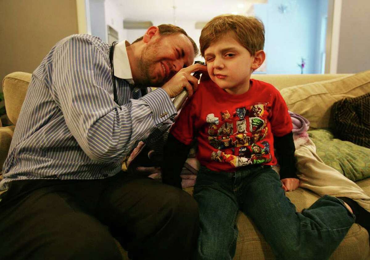 Dr. Edward Kulich of Brooklyn looks in the ears of patient Julian Frucht, 7, during a housecall at the Frucht's Westport home on Sunday, February 13, 2011.