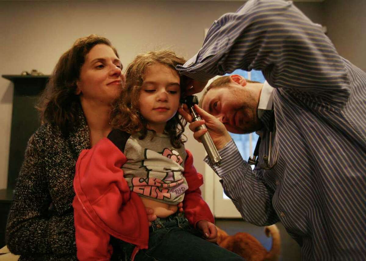 Elizabeth Besen holds her daughter Genevieve Frucht, 5, as she is examined by Dr. Edward Kulich of Brooklyn, NY, during a housecall at their Westport home on Sunday, February 13, 2011.