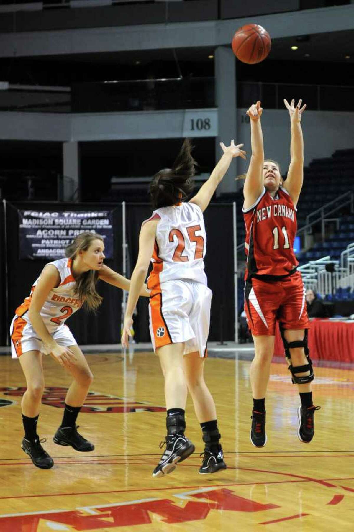 New Canaan's Courtney Rogers takes a shot as Ridgefield's Molly Welch, center, and Lauren Eckstrom, left, defend during Tuesday's FCIAC girls basketball semifinal game at the Webster Bank Arena at Harbor Yard on Feburary 22, 2011.