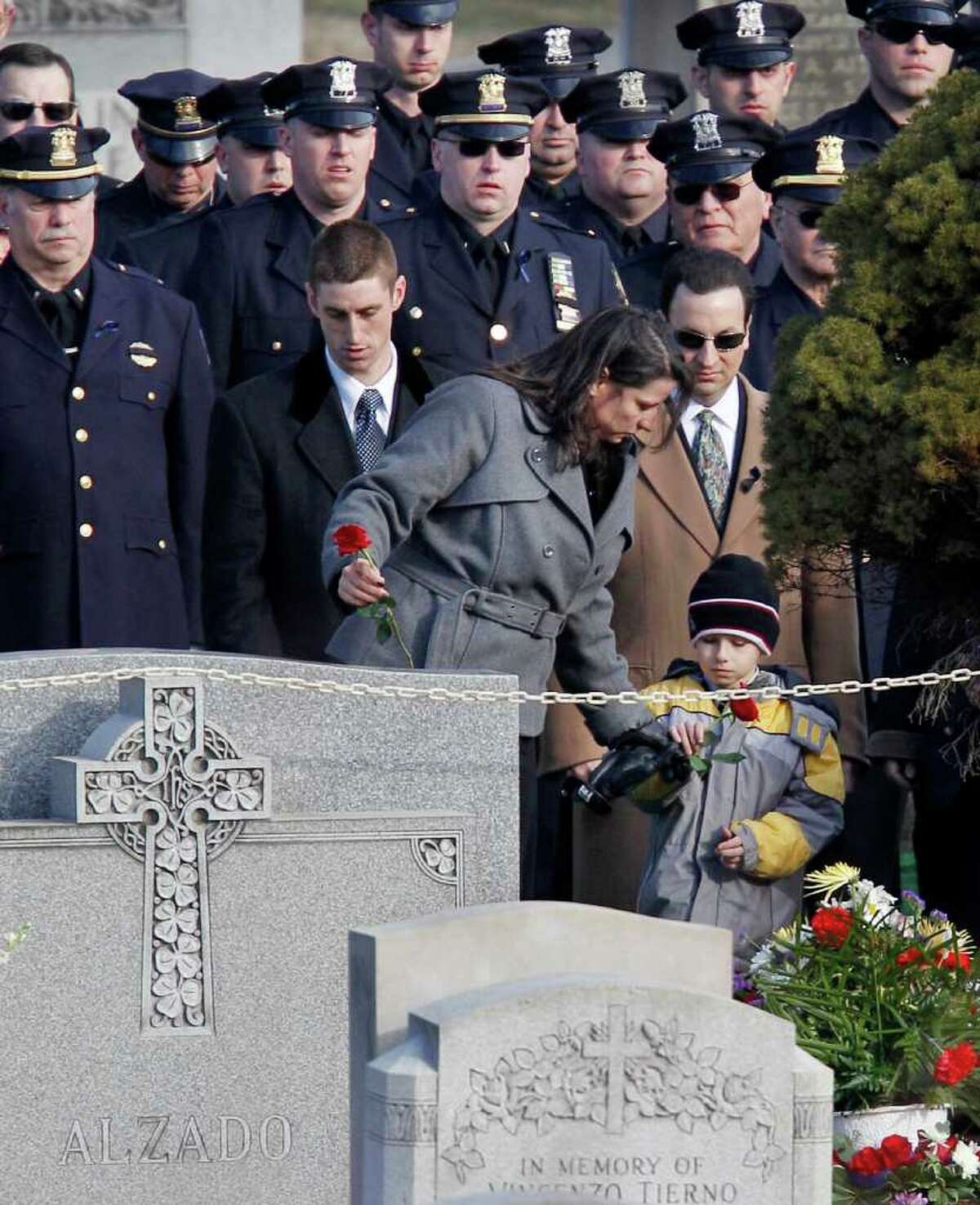 Relatives of slain Poughkeepsie police Detective John Falcone, 44, lay carnations at his gravesite during burial for the 14-year police veteran at Brooklyn's Holy Cross Cemetery in New York, Thursday, Feb. 24, 2011. Falcone was killed as he helped rescue a 3-year-old girl. (AP Photo/Kathy Willens)