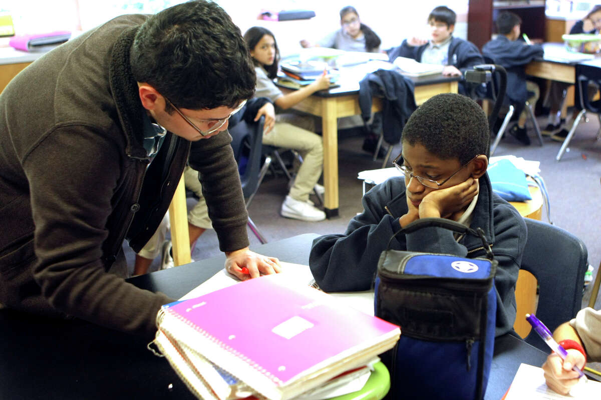 Science teacher Adam Gomez answers a question for Isaiah Dickson, 11, at KIPP San Antonio's Camino Academy, one of three schools the charter district operates.